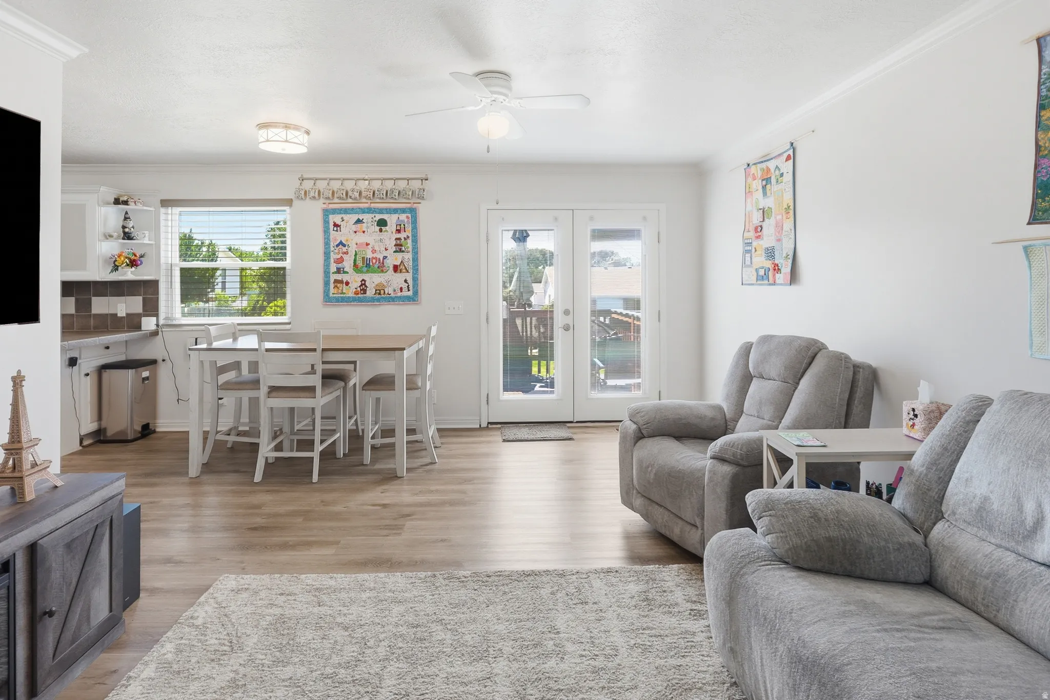 Open-concept living area featuring wood-finish flooring, white walls, and crown molding