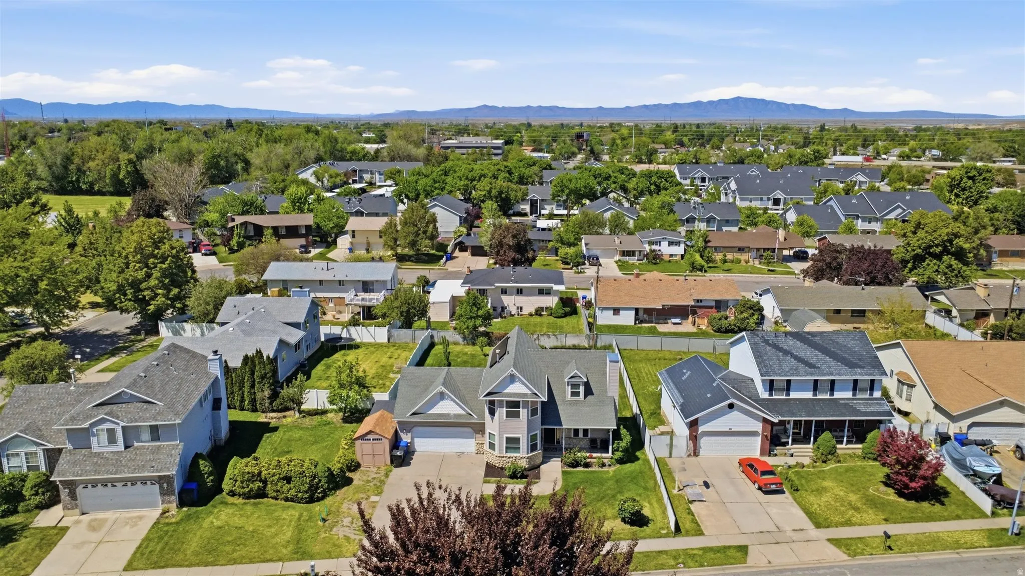 Suburban neighborhood featuring a variety of residential properties, mature trees, and distant mountain ranges
