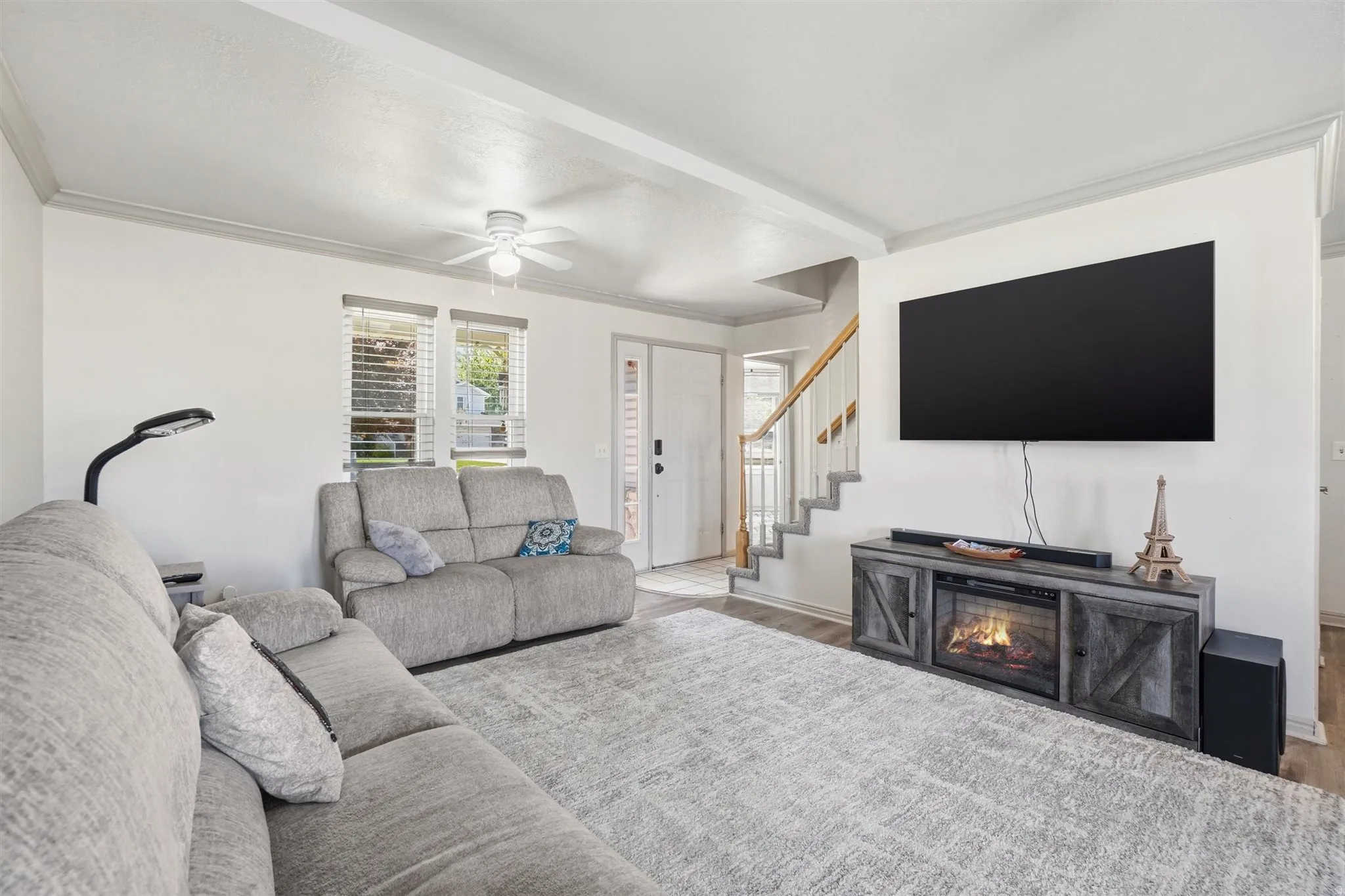 Spacious living area featuring light-toned walls and wood-finish flooring