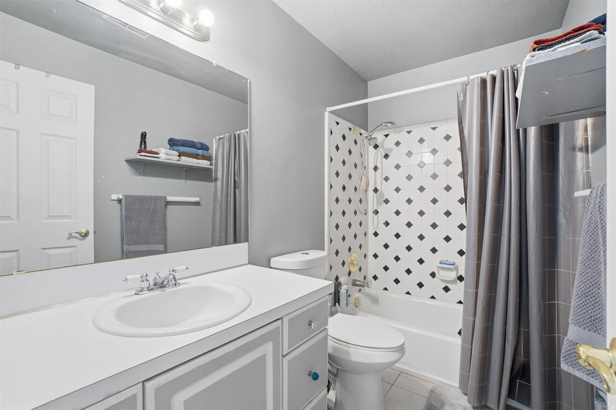 Bathroom featuring a white vanity with an integrated sink, a large wall-mounted mirror, and a three-bulb vanity light fixture