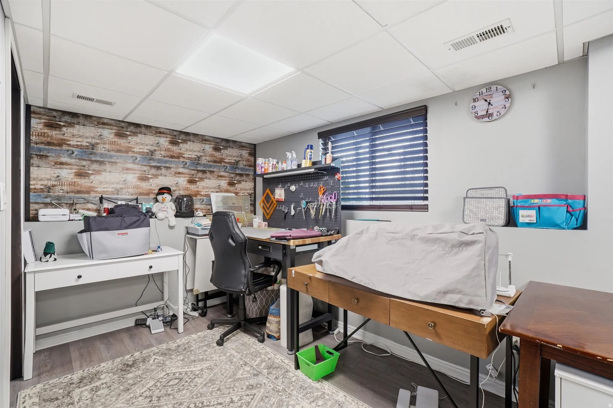 Finished room featuring a wood-look accent wall and suspended ceiling with recessed lighting