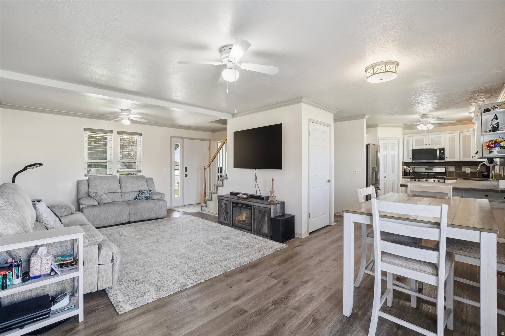 Open-concept living space featuring wood-finish flooring, white walls, and crown molding