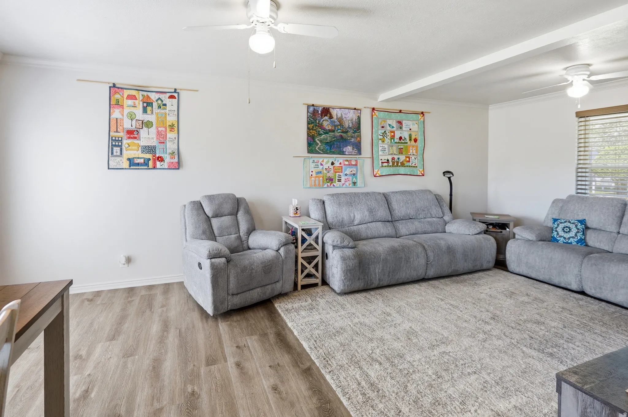 Spacious room featuring wood-finish flooring, white walls, and a recessed ceiling beam