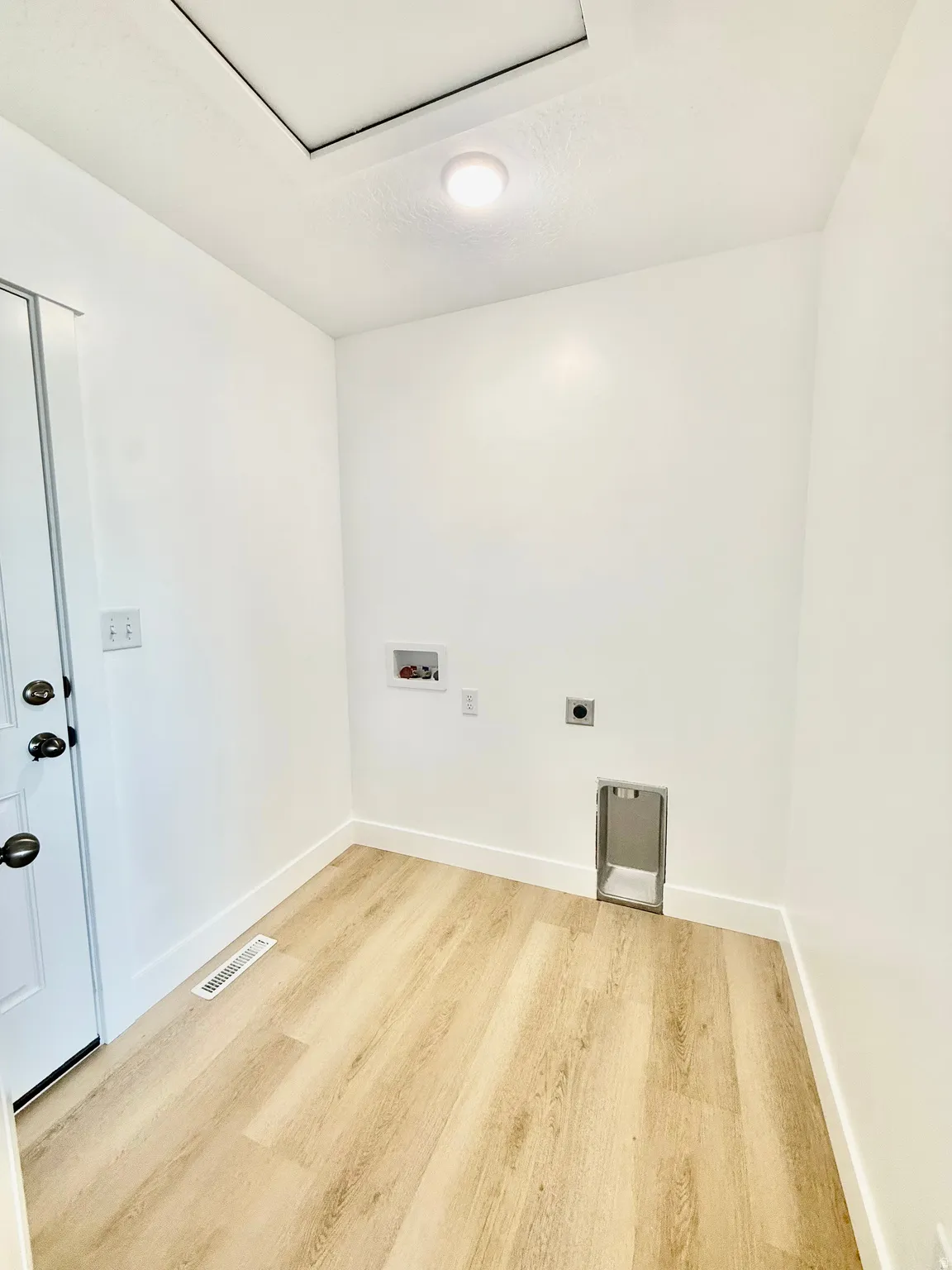 Dedicated laundry area featuring light wood-finish flooring and white baseboards