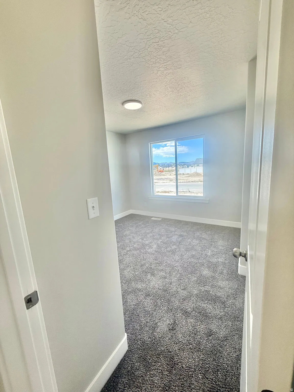 Spacious room featuring neutral grey walls and new grey carpeting