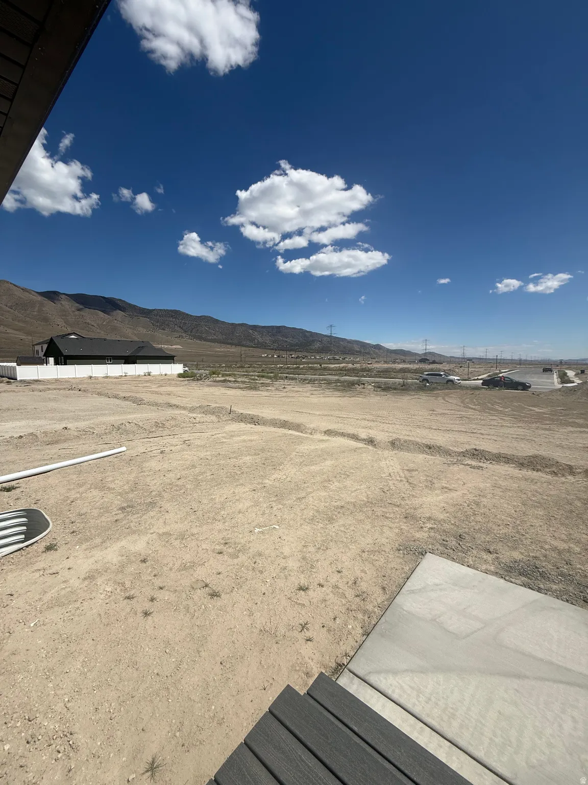 Expansive undeveloped lot with mountain backdrop, featuring a concrete pad and dark composite decking