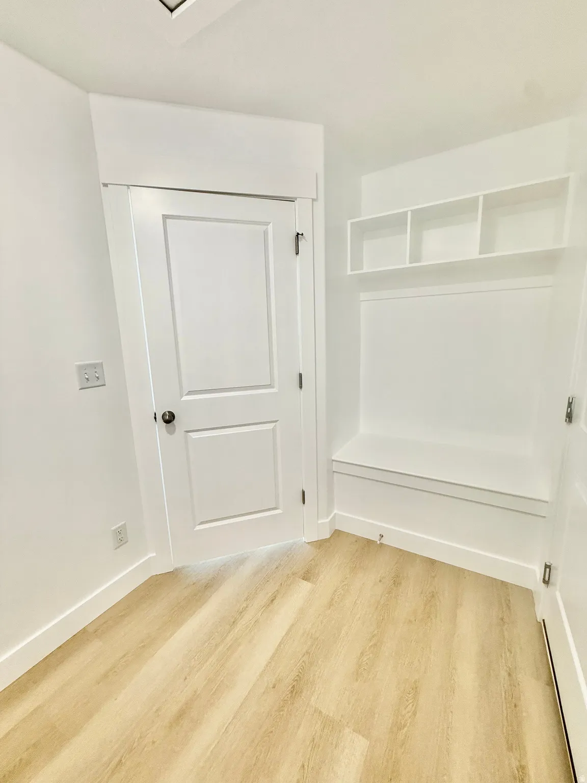 Built-in bench with upper cubby storage, wood-finish flooring, and crisp white trim