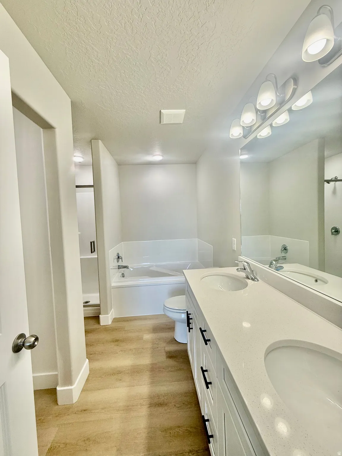 Dual vanity with integrated sinks, light-toned countertop, and wood-finish flooring
