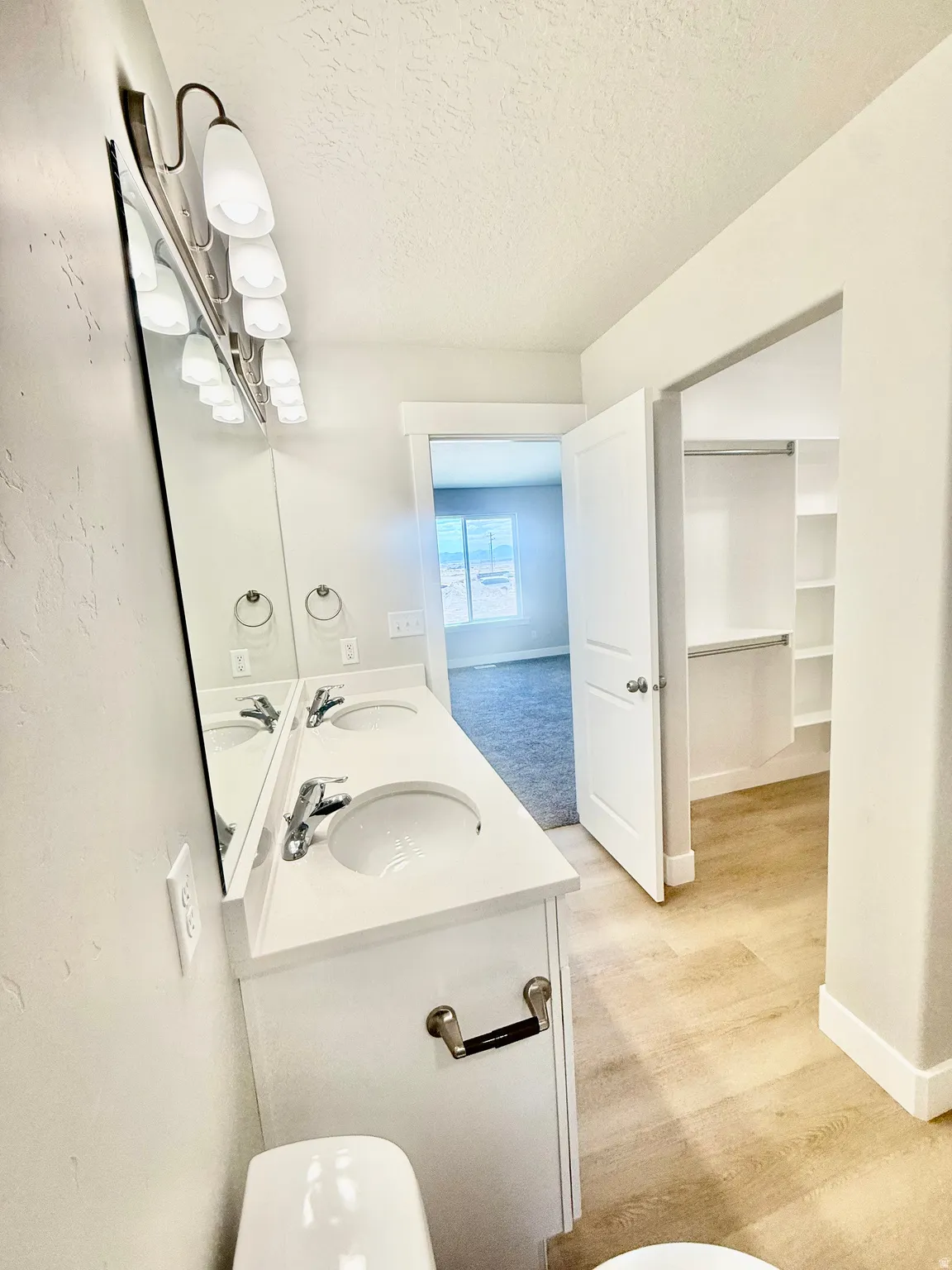 Bathroom featuring a dual-sink vanity with chrome fixtures and a large wall-mounted mirror