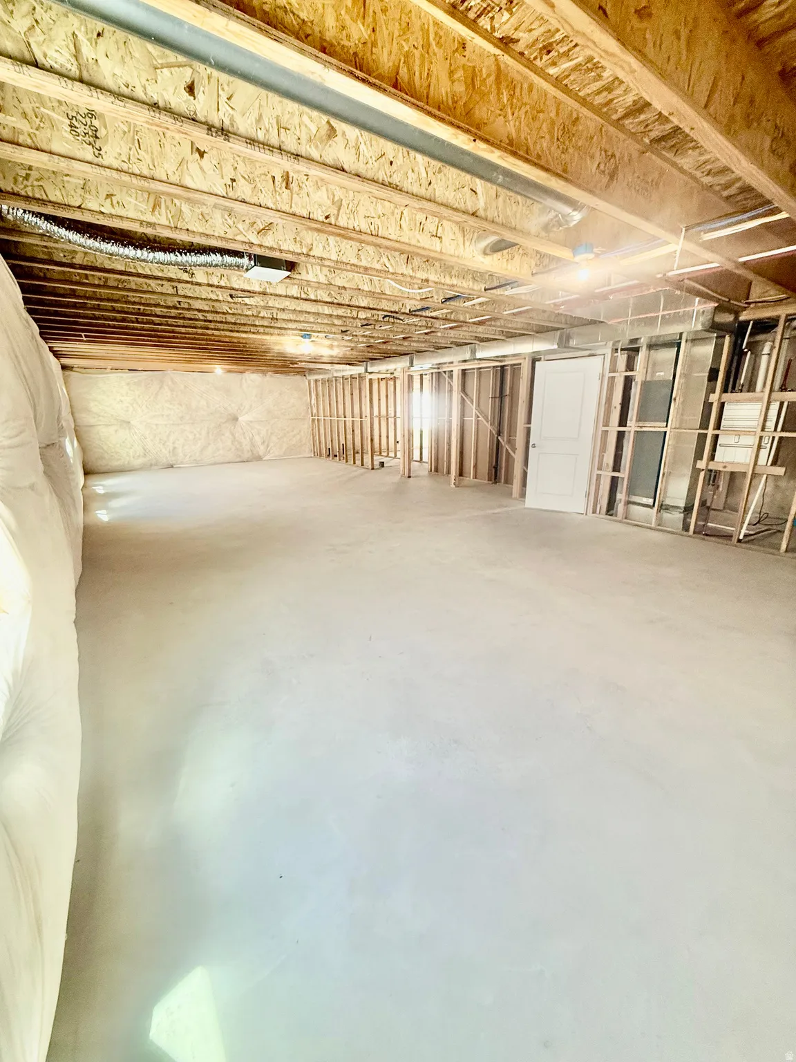Unfinished basement with concrete flooring, exposed wood joists, and framed partition walls