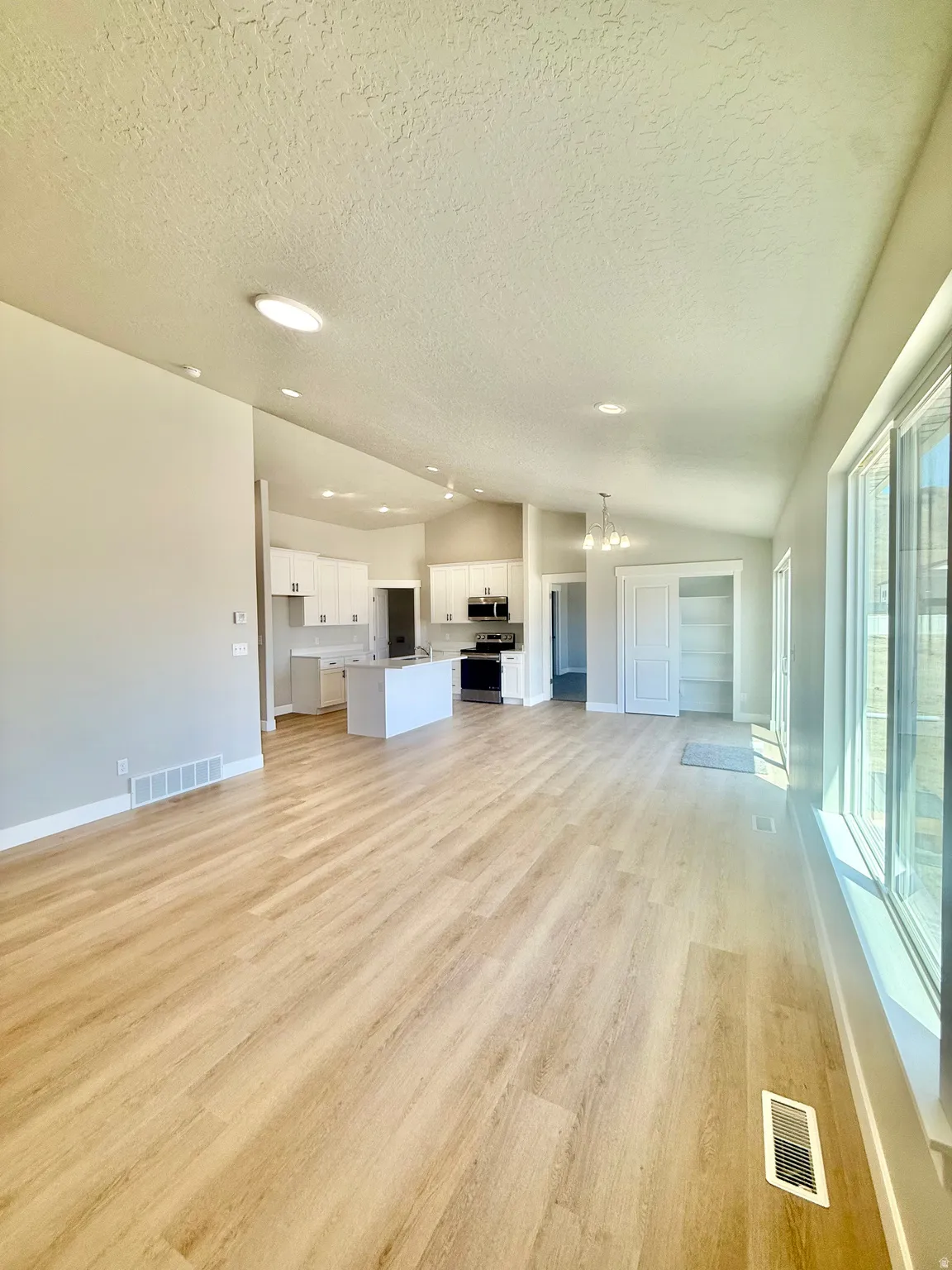 Open-concept living area featuring wood-finish flooring, recessed lighting, and expansive windows