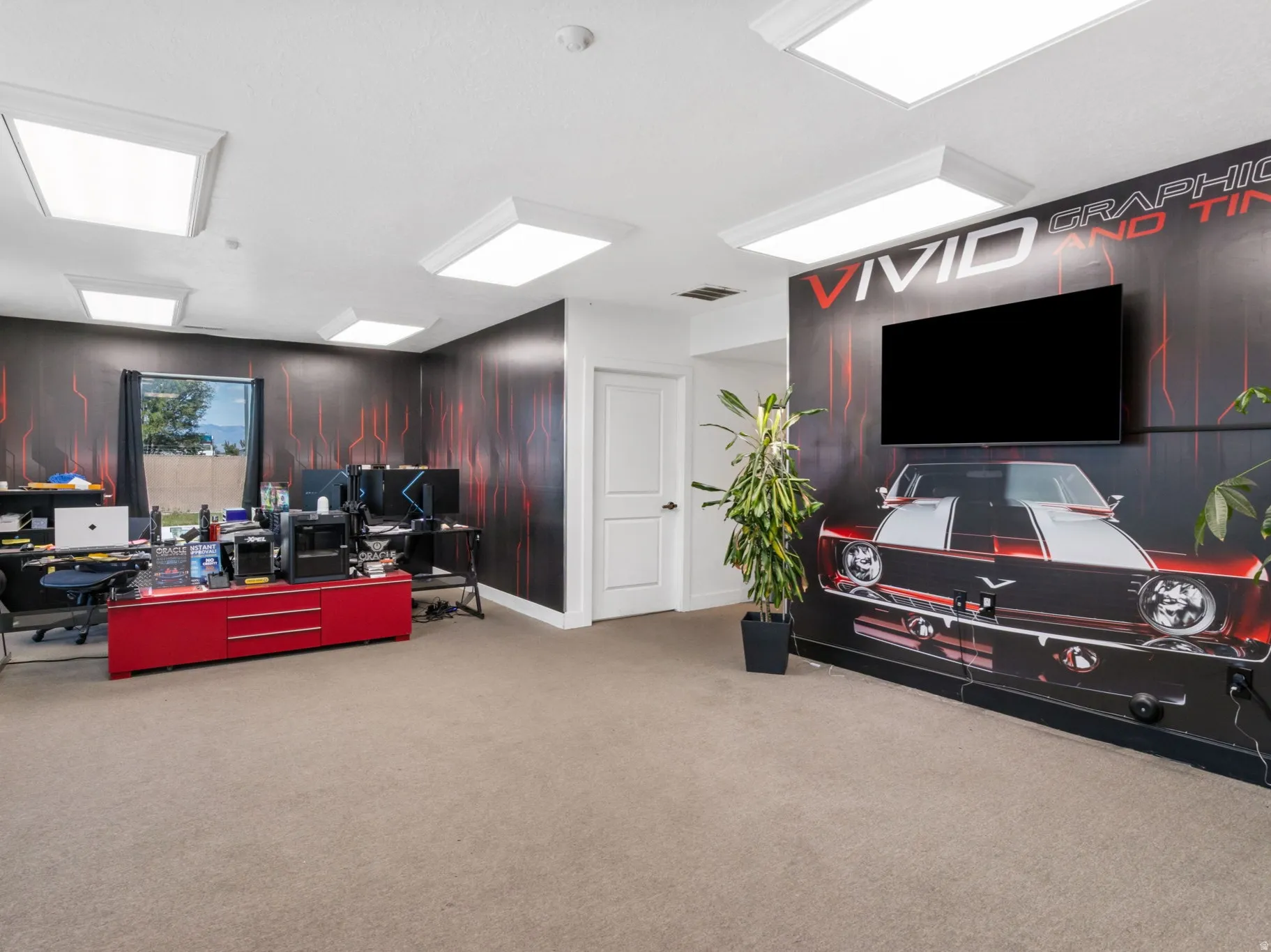 Spacious room featuring carpet flooring, recessed lighting, a large window, and a wall-mounted display