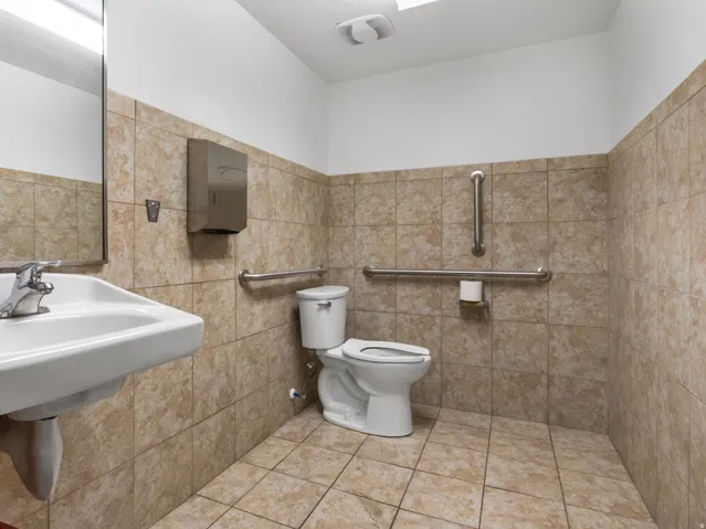 Restroom featuring a wall-mounted sink, chrome faucet, and rectangular mirror