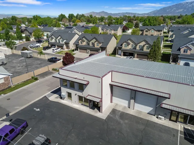 Commercial building featuring a metal roof, multiple bay doors, and an expansive paved parking area