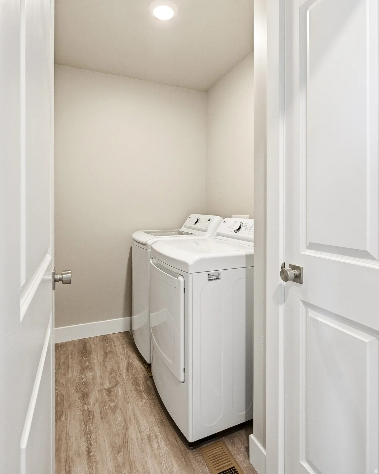 Dedicated laundry area featuring wood-finish flooring, light neutral wall paint, and recessed ceiling lighting