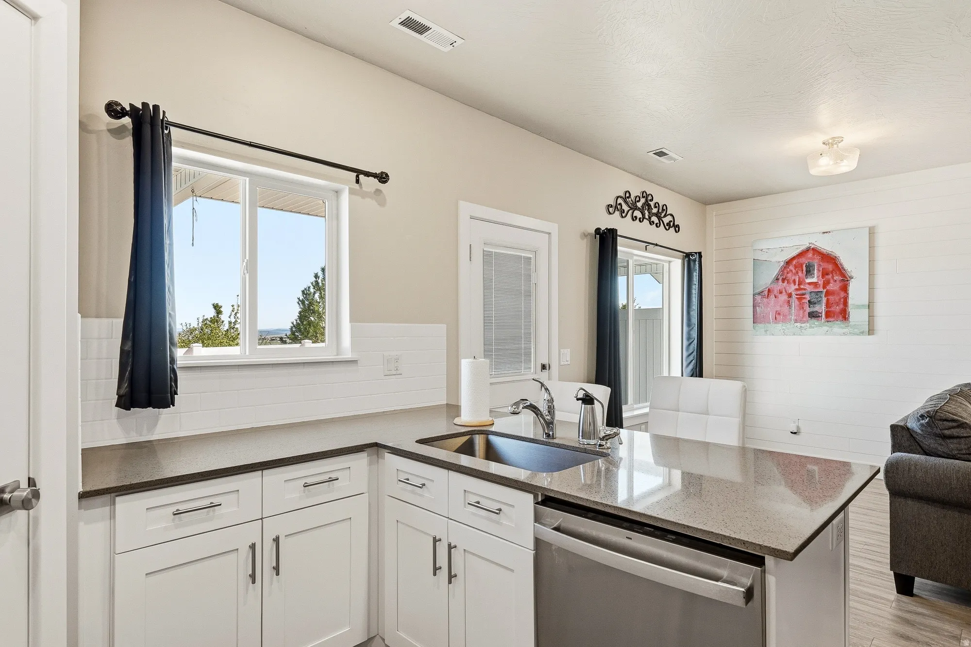 Kitchen featuring white cabinetry, a stainless steel sink, and light-toned countertops