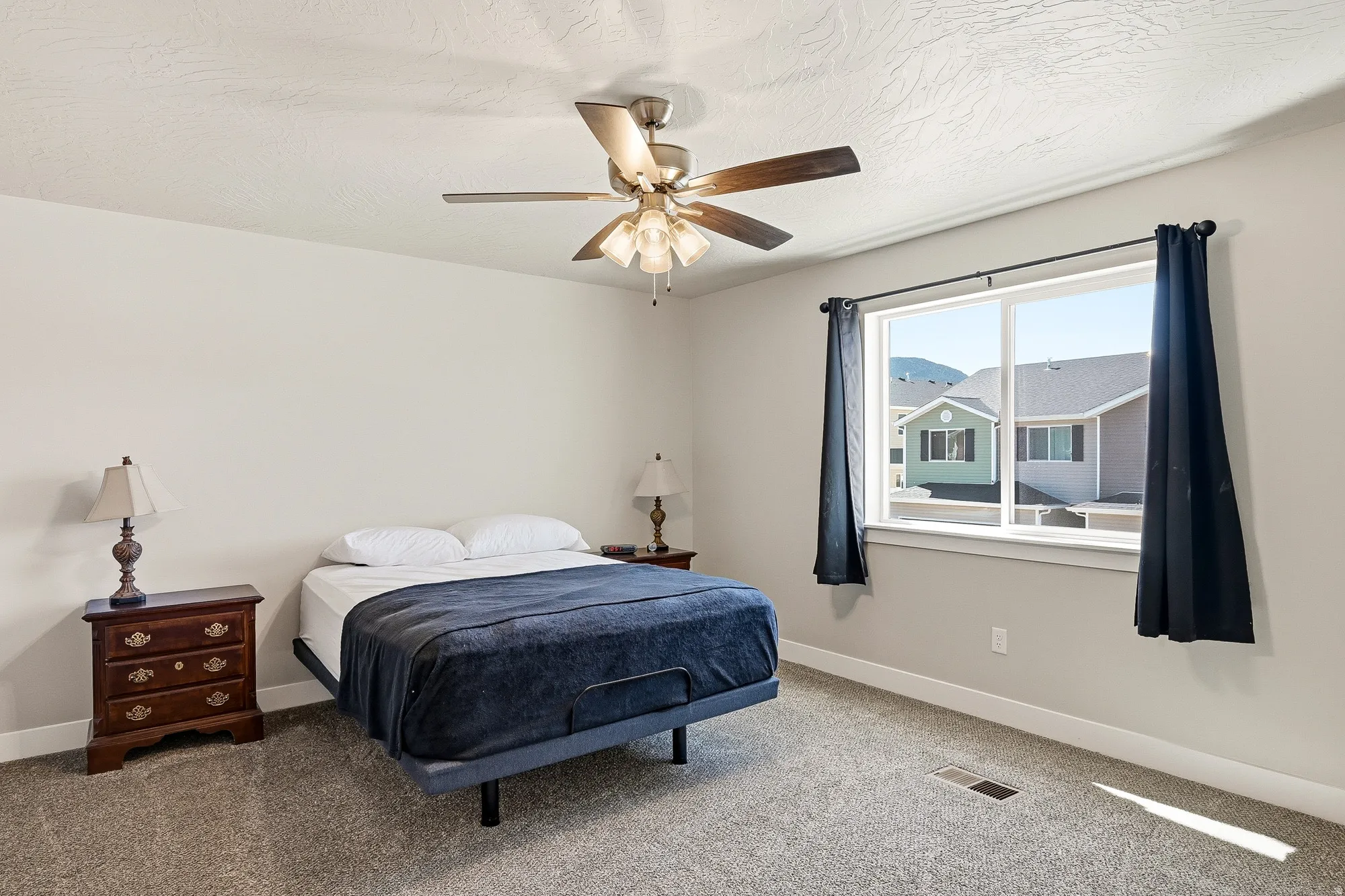 Bedroom featuring a ceiling fan with light kit, carpeted flooring, and a large window with white trim
