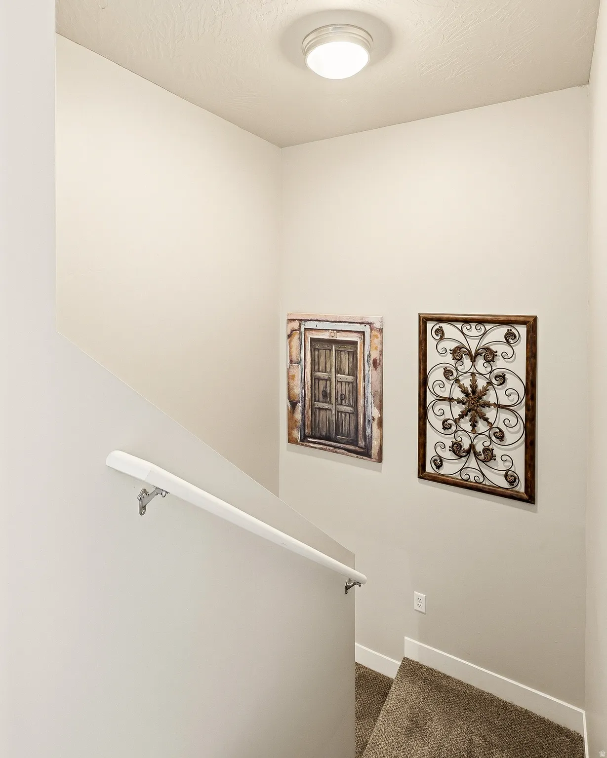 Interior staircase featuring a neutral color palette, durable carpet flooring, and a white wall-mounted handrail