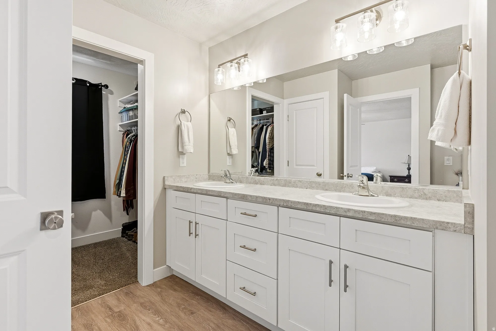 Double vanity with white shaker cabinetry, brushed nickel hardware, and light-toned countertop