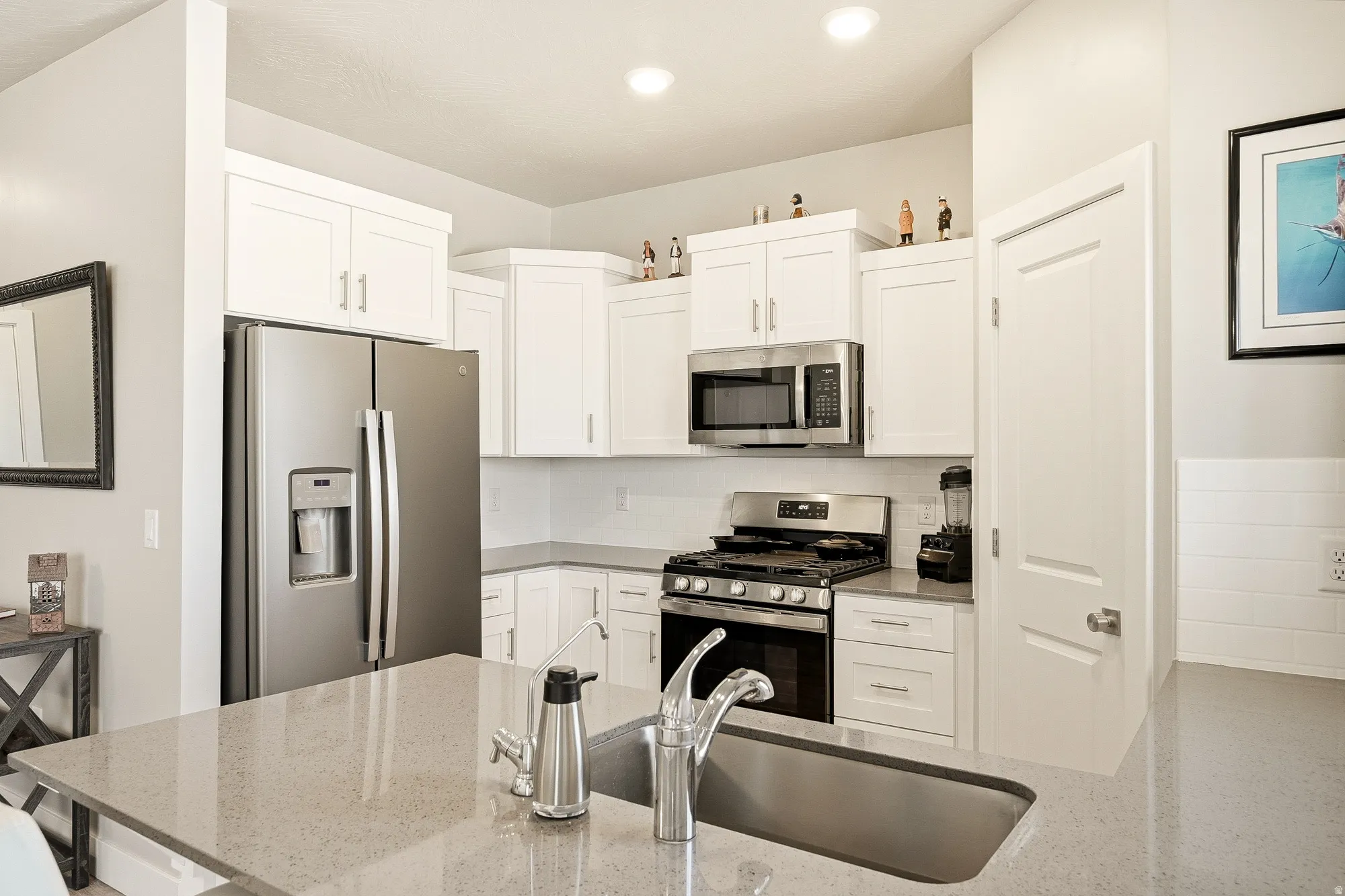 Kitchen featuring white shaker cabinetry, stainless steel appliances, a gas range, and a subway tile backsplash