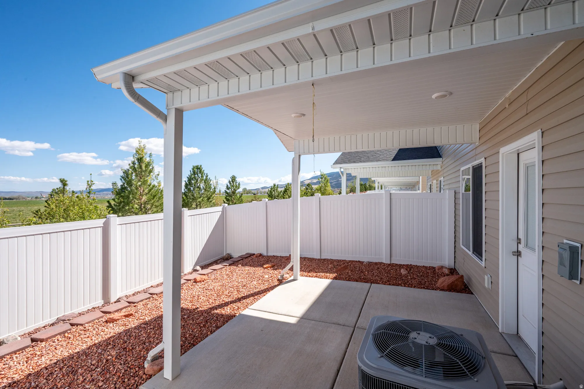 Covered patio with concrete flooring, accented by red gravel and stepping stones