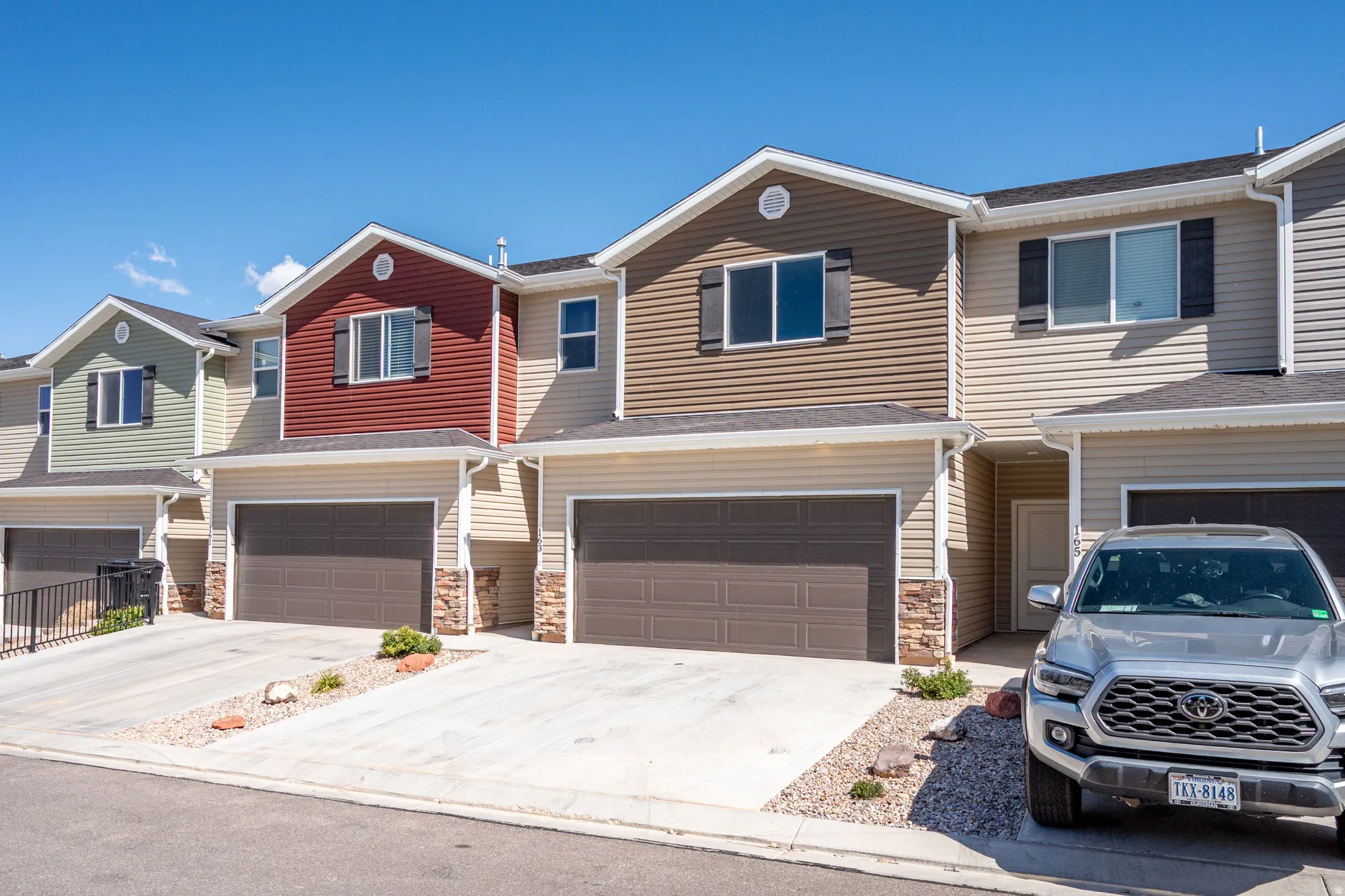 Townhome exterior featuring diverse siding colors, attached garages, and individual entryways
