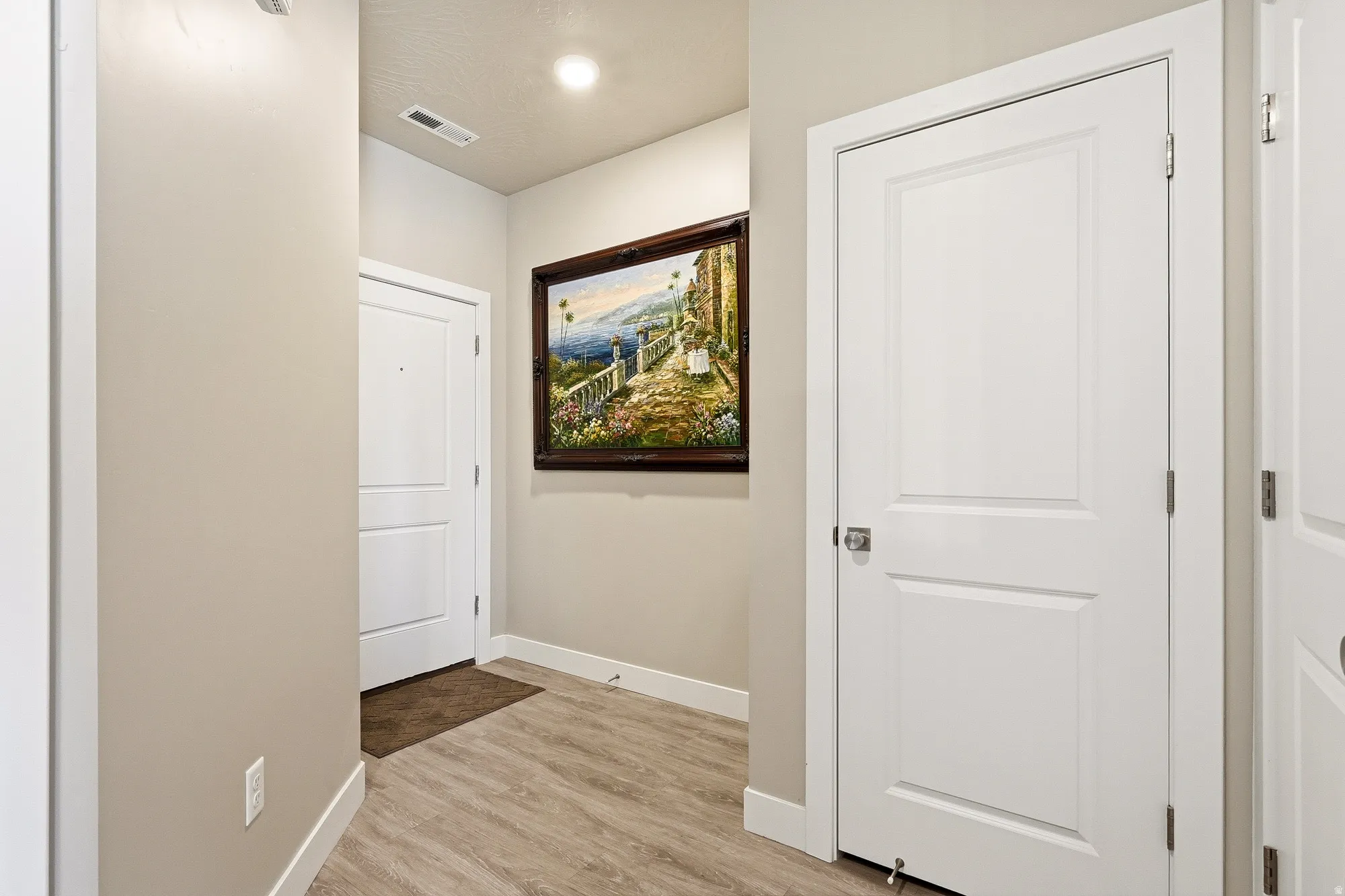 Entryway featuring wood-finish flooring, light neutral wall paint, and white trim