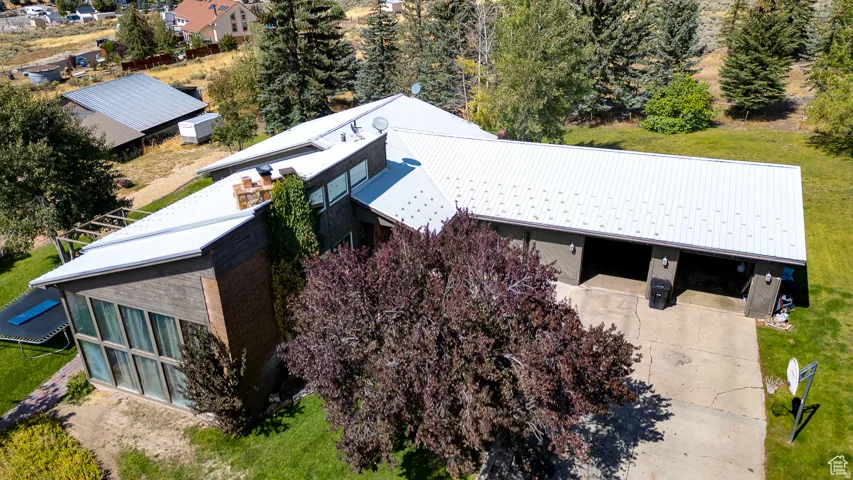 Contemporary-style residence featuring a metal roof, brick and wood-panel exterior, a multi-car garage, and a lush green lawn