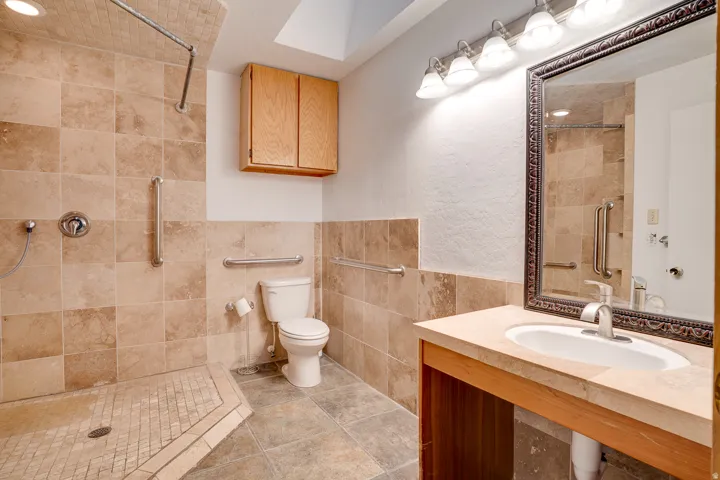Walk-in shower with tiled walls and floor, featuring a built-in grab bar