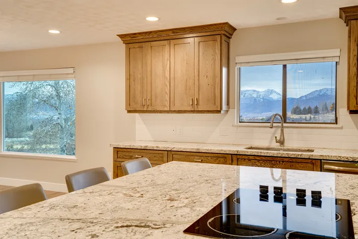 Kitchen featuring light wood cabinetry, granite countertops, a white subway tile backsplash, and a built-in cooktop on the island