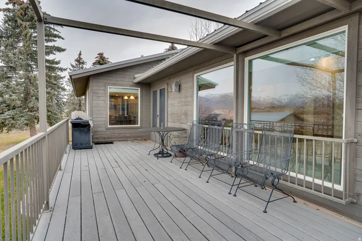 Expansive outdoor deck featuring wood-finish flooring, a full-height railing, and overhead pergola framing