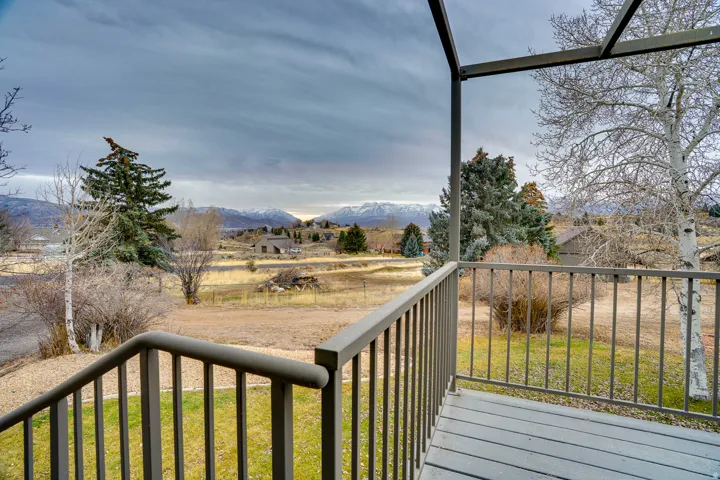Expansive outdoor deck with gray railing and decking, offering distant mountain scenery and mature trees