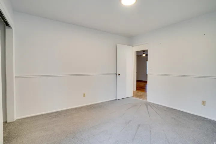 Carpeted room featuring white walls, chair rail molding, and a flush mount ceiling light