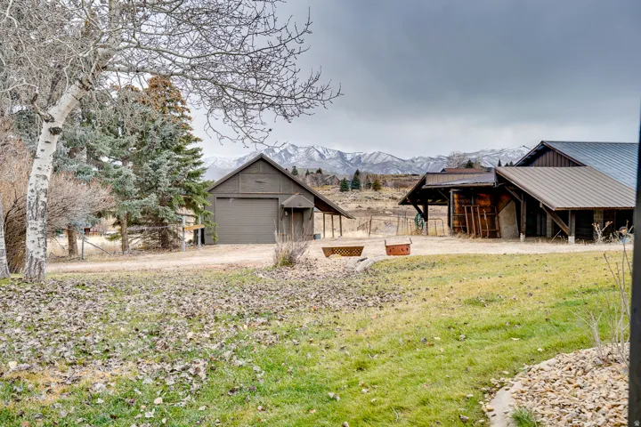 Expansive grounds featuring multiple outbuildings, including a garage structure with a single bay door and an adjacent covered entry