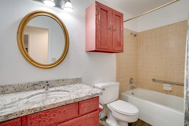 Bathroom vanity with a white countertop featuring an oval undermount sink and chrome faucet