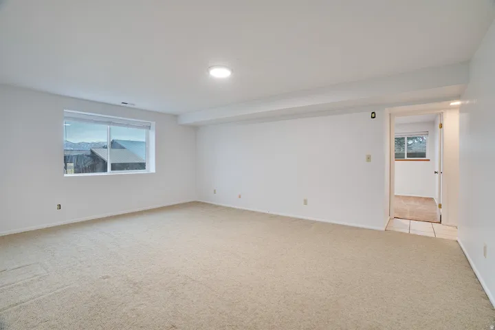 Spacious room featuring neutral carpeting, a large window, white walls, and recessed lighting