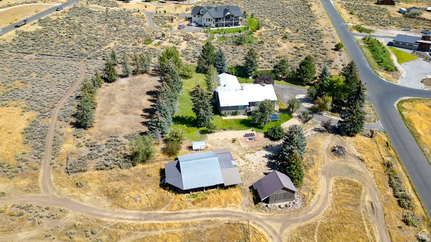 Expansive property featuring a main residence, two outbuildings, a paved drive, mature trees, and a fire pit area