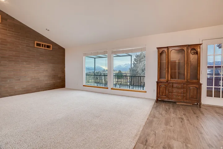 Spacious interior featuring a vaulted ceiling and a prominent brick accent wall