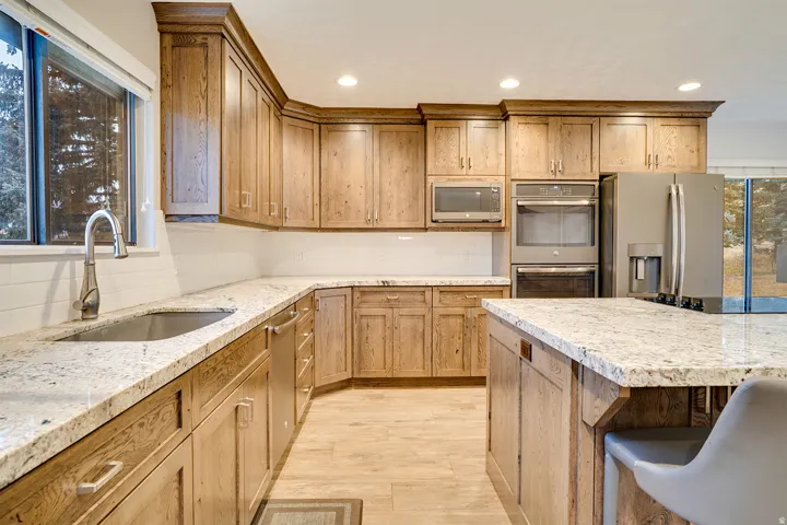 Kitchen with wood-finish cabinetry, light-toned countertops, and stainless steel appliances