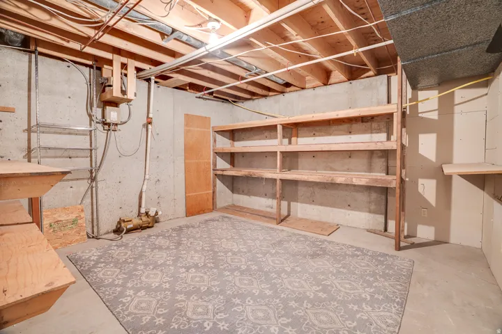 Unfinished basement space featuring exposed concrete walls and ceiling joists