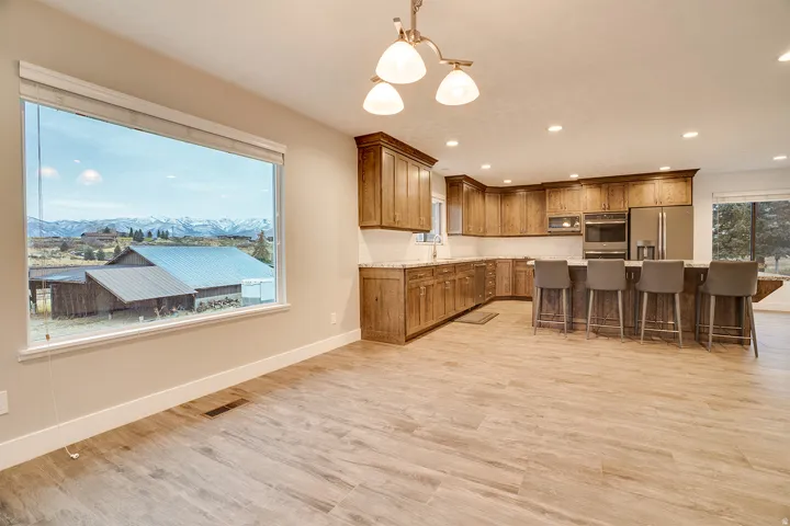 Expansive kitchen and dining area featuring wood-finish flooring, recessed lighting, and a large window