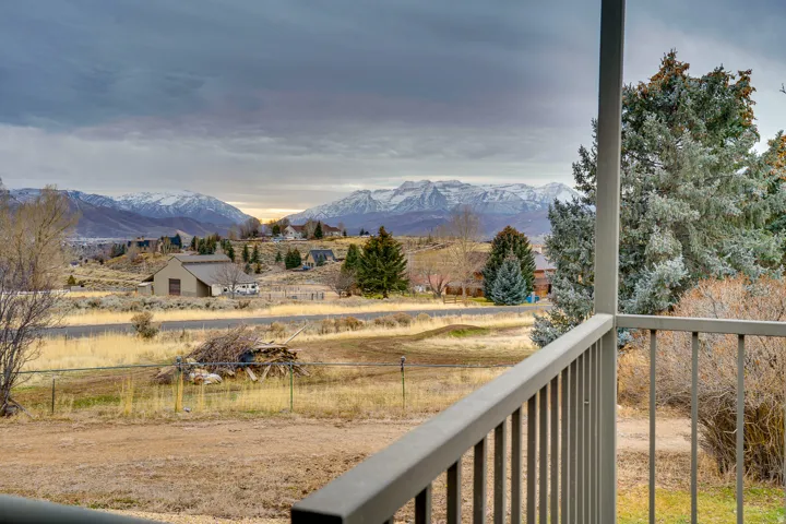 Outdoor balcony with metal railing overlooking a landscape featuring distant snow-capped mountains