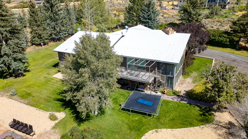 Expansive multi-level residence with a white metal roof and a full-height glass sunroom