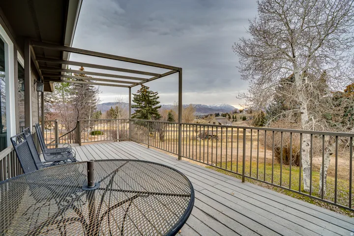 Expansive outdoor deck featuring wood-finish flooring, metal railing, and a partial pergola structure