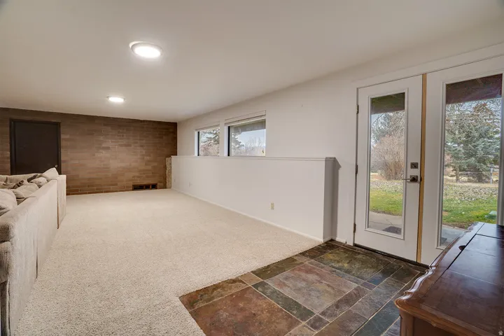 Spacious room featuring a brick accent wall, recessed lighting, and light-colored carpeting