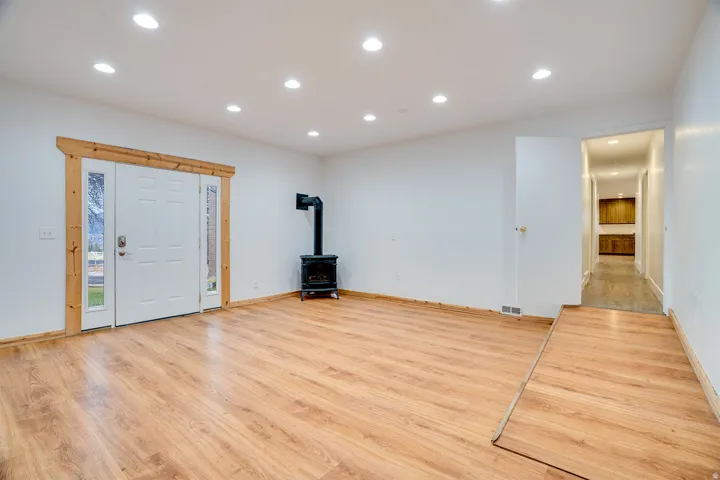 Open living space featuring wood-finish flooring, recessed lighting, and a freestanding black stove