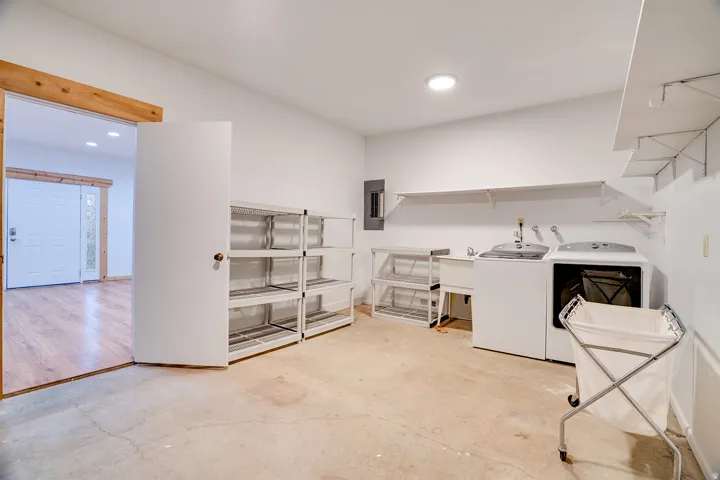 Dedicated laundry area featuring a utility sink, wall-mounted shelving, and a durable concrete floor
