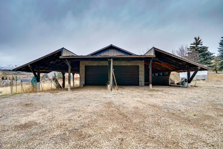 Detached garage structure featuring two roll-up doors, concrete block construction, and an extended carport with exposed wood framing