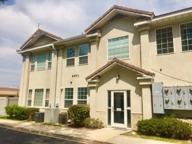 Two-story stucco building featuring a red tile roof and multiple window panels