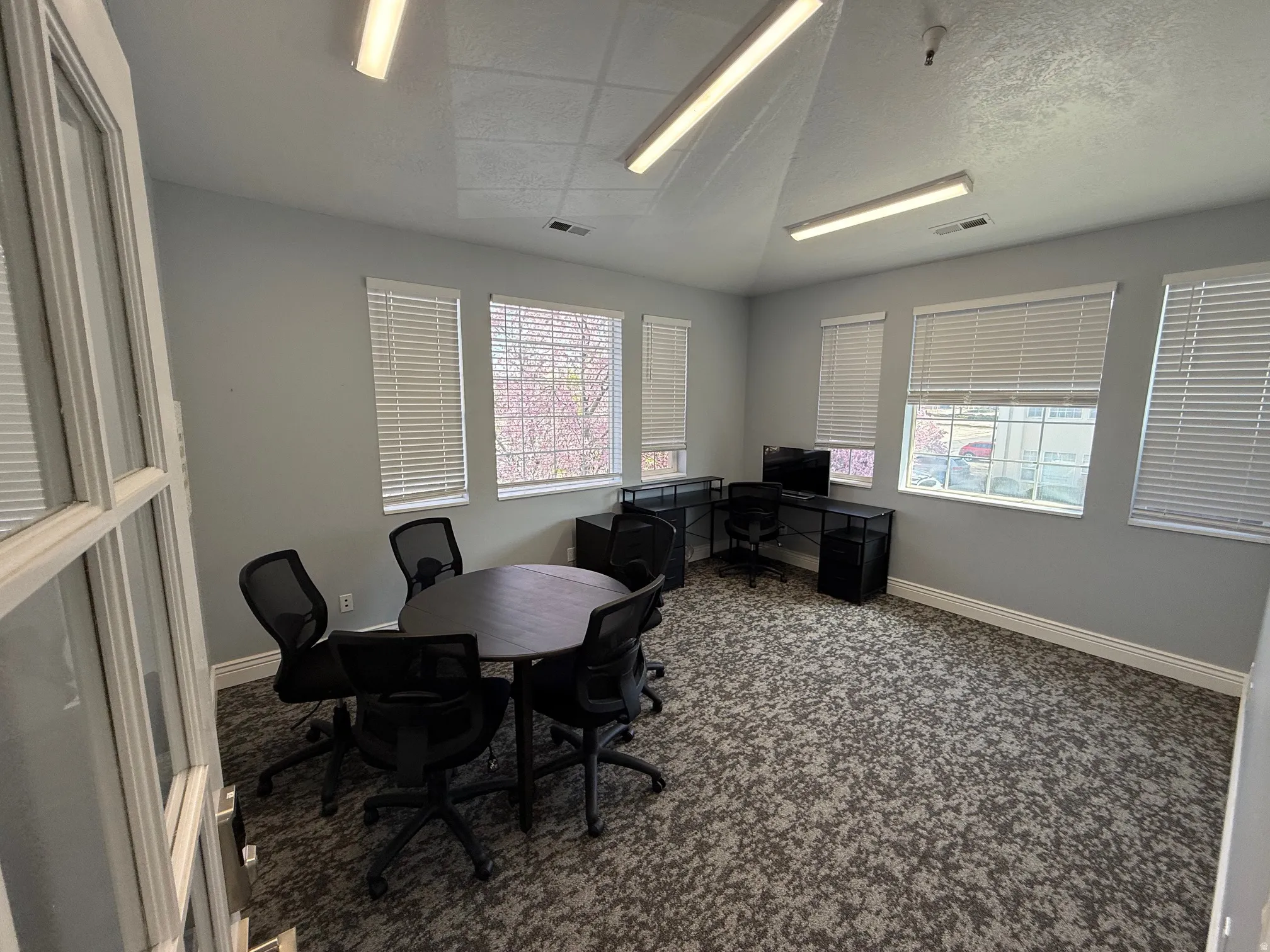 Spacious room featuring multiple windows with blinds, gray wall paint, patterned carpeting, and recessed lighting